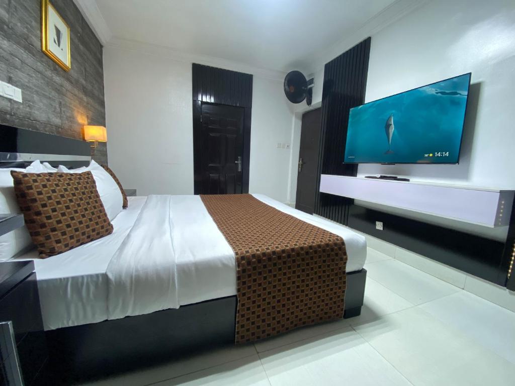 a bedroom with a bed and a flat screen tv at Newland Luxury Hotels and Apartments in Abuja