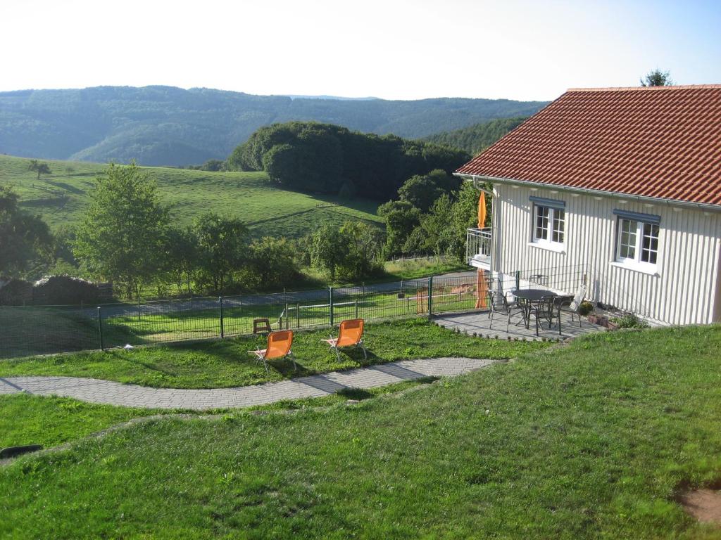 una pequeña casa blanca con sillas naranjas en el césped en Ferienhof Rothenberg, en Rothenberg