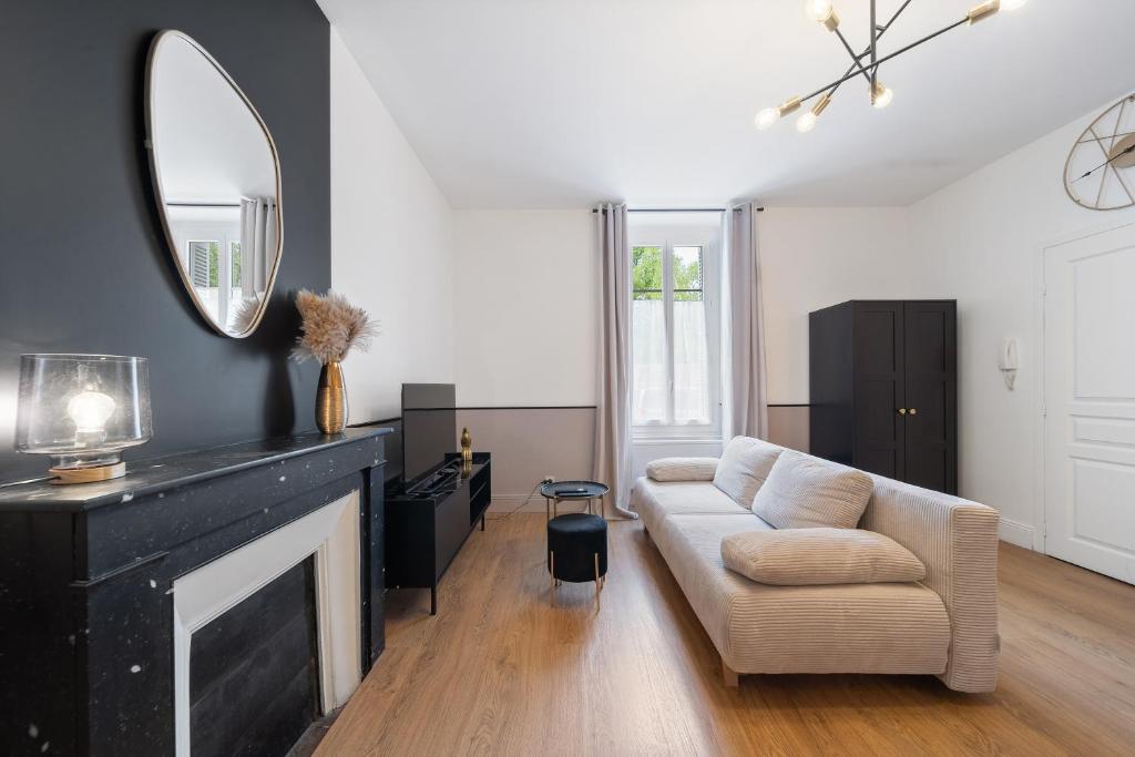 un salon avec un canapé et un miroir dans l'établissement Charme & Tranquillité : Jardin de l’Arquebuse/Gare, à Dijon