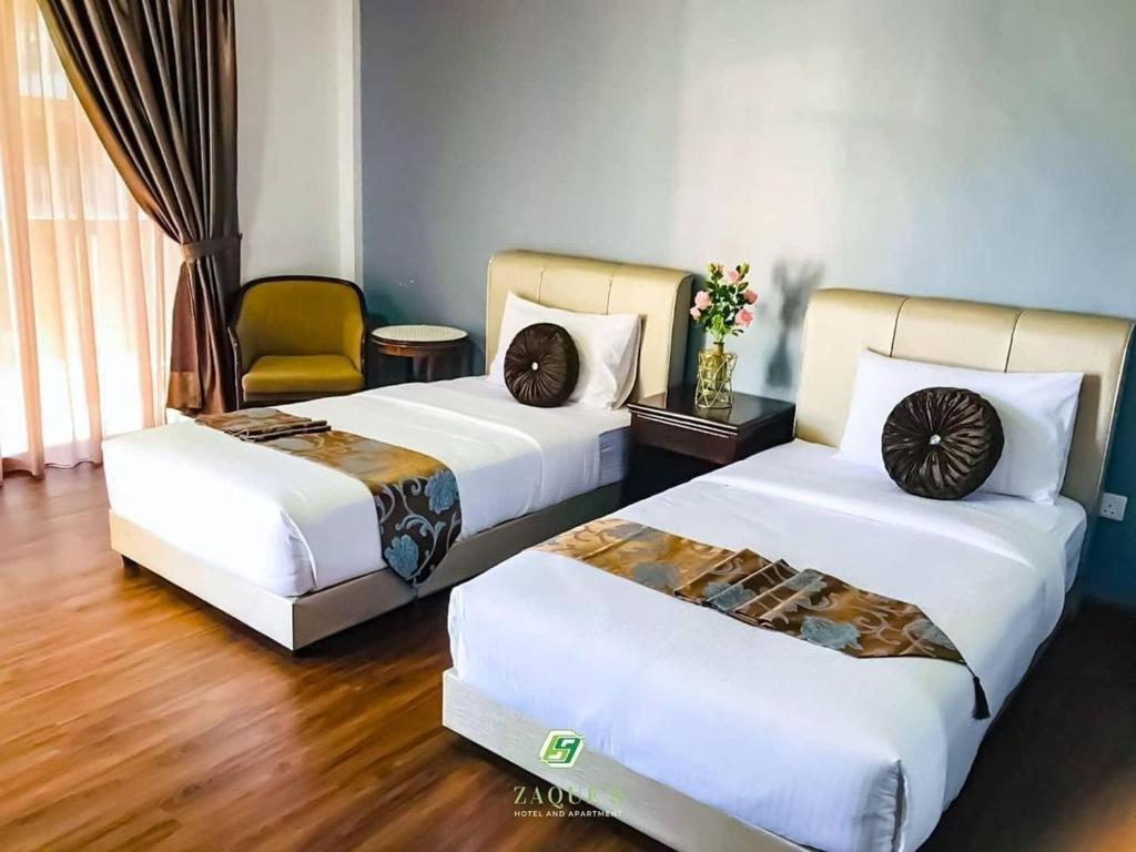 a hotel room with two beds and a chair at Zaque's Hotel in Sungai Petani