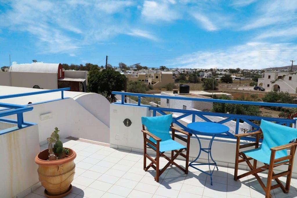 uma varanda com cadeiras azuis e mesas num telhado em Santorini Seaside Retreat - Flora's Summer Escape em Perissa