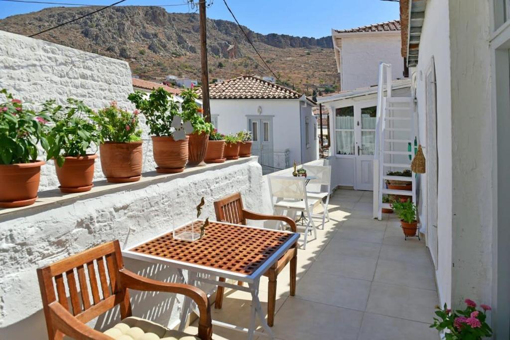 a patio with a table and chairs and potted plants at A Sea-licious Vacation - Chic & Style in Hydra in Hydra