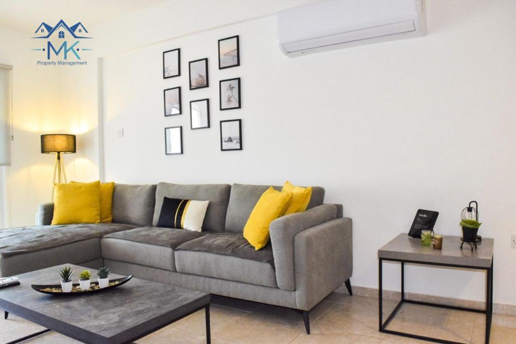 ein Wohnzimmer mit einem grauen Sofa und gelben Kissen in der Unterkunft SeaWitch Apartment in Larnaka
