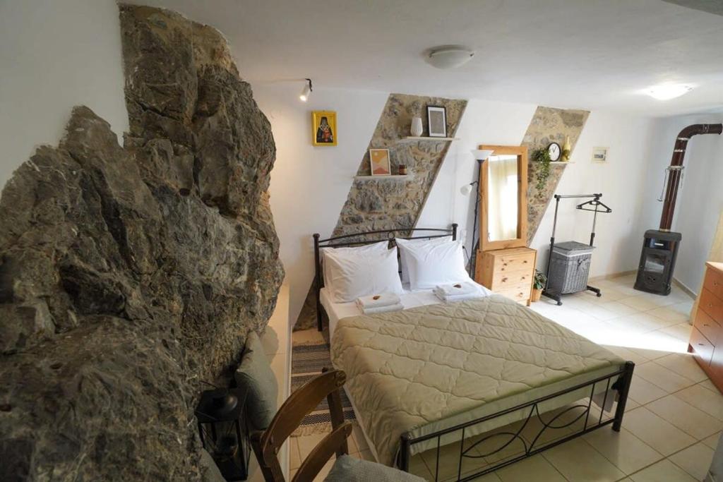 a bedroom with a bed in a rock wall at Vilaeti Stone House - Cretan Cozy Nest in Agios Konstantinos