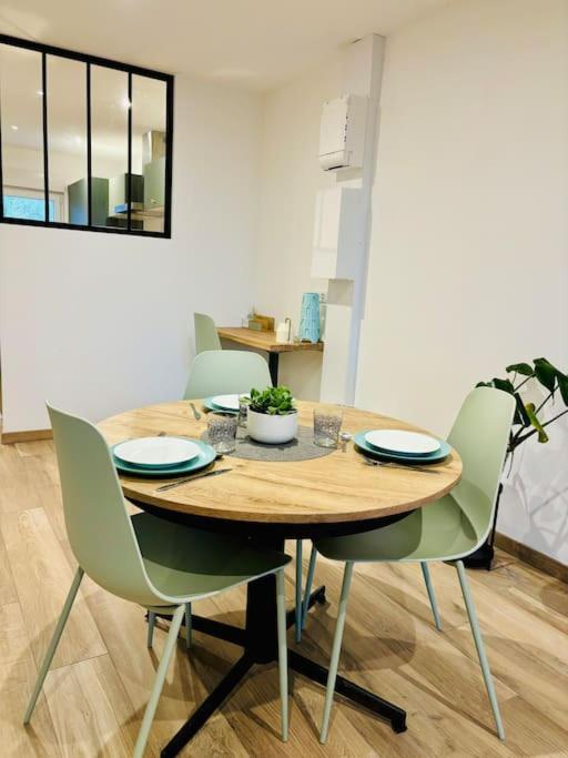 une table en bois avec des chaises et une salle à manger dans l'établissement Maison au calme, à la campagne, à Fontenay-le-Marmion