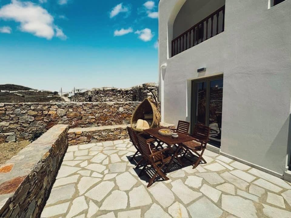Captain's Villa - Sea Serenity in Folegandros في Áno Meriá: فناء مع طاولة وكراسي بجوار مبنى