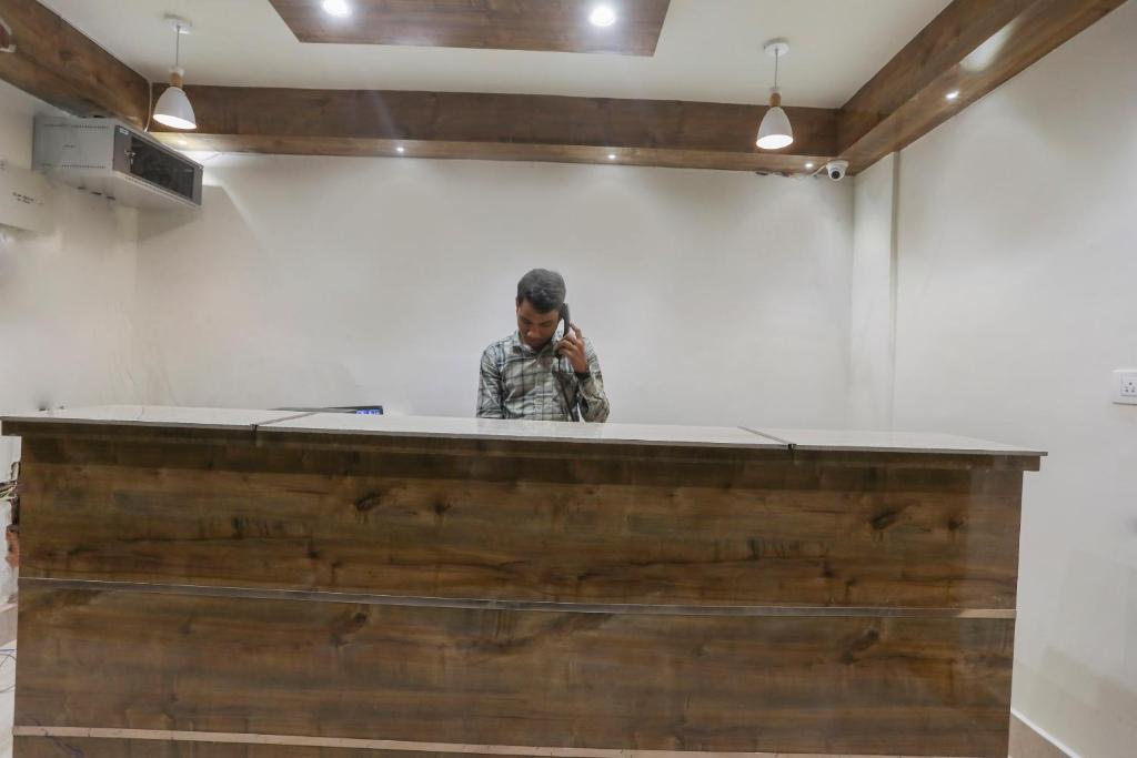 a man talking on a cell phone behind a counter at OXY Royal Residency in Rānchī