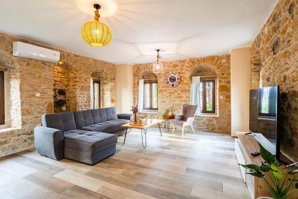 a living room with a couch and a tv at Mantineia Stone Villa-An Ethereal Getaway in Megáli Mandínia