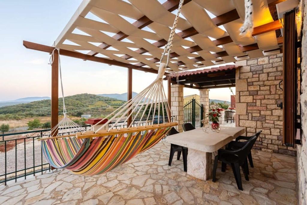 a hammock on a patio with a table and chairs at Polilimnio Mini Castle - Fotini's Unique Eco Gem in Aristoménis
