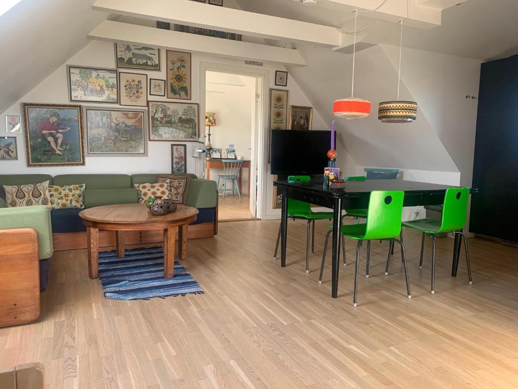 SøndersøにあるDrejerindens kreative stemningsfulde lejlighedのリビングルーム(テーブル、緑の椅子付)