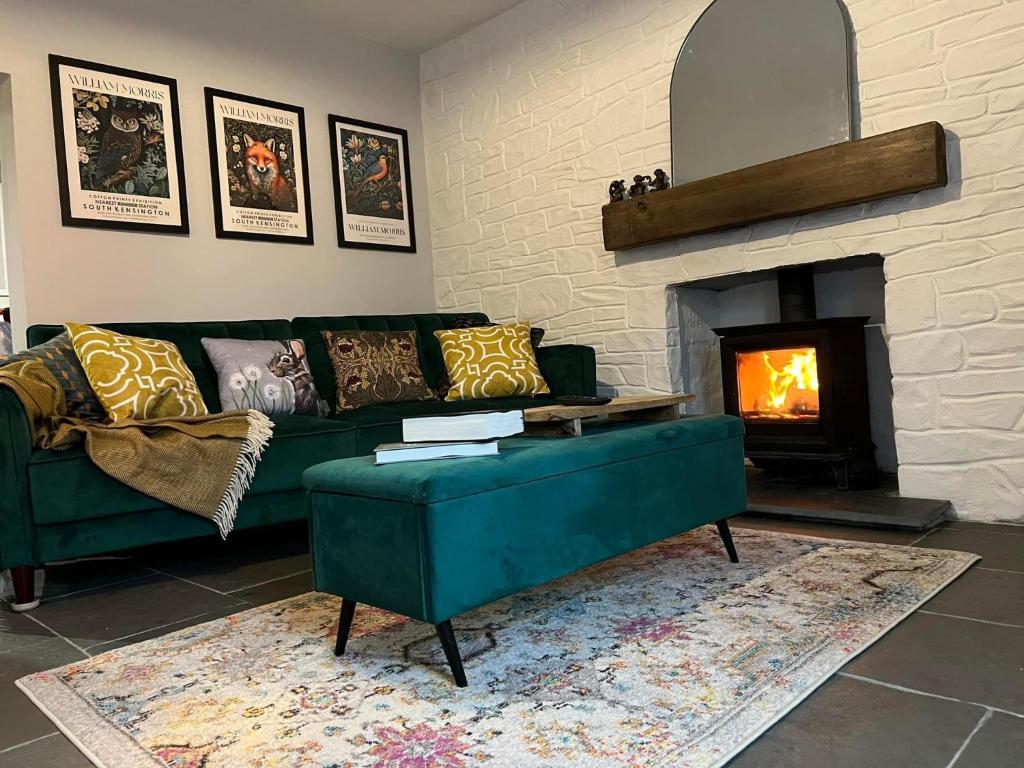 a living room with a green couch and a fireplace at Charming 2-Bed House in Llansteffan in Llanstephan