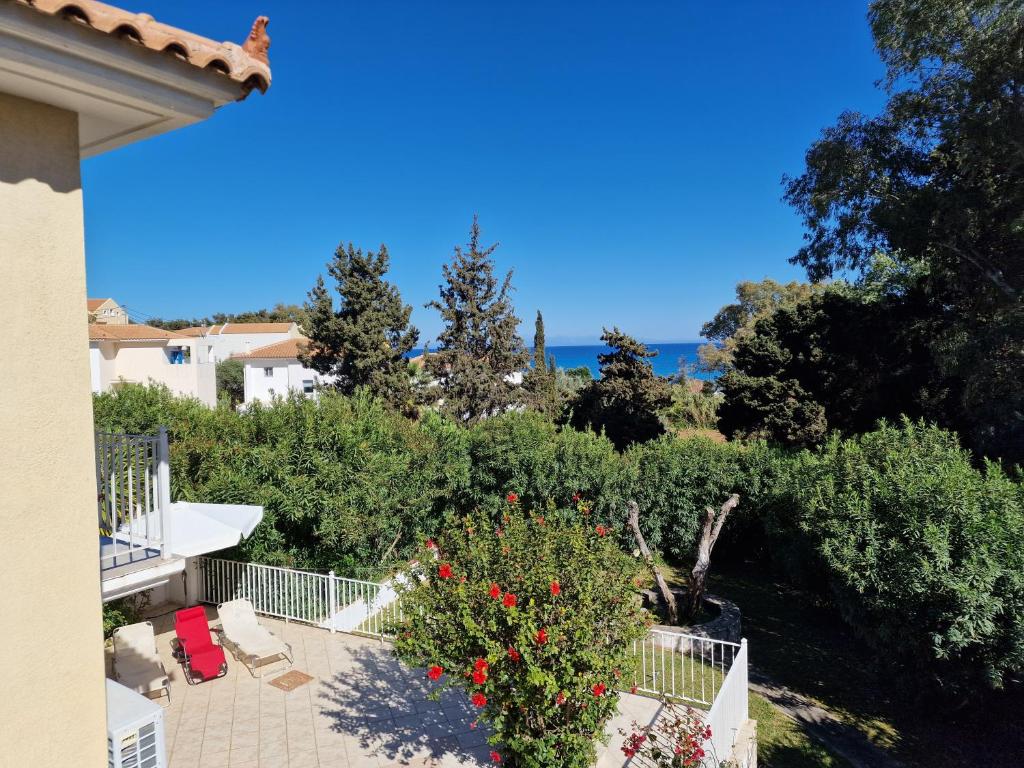 a view from the balcony of a house with a bush with red flowers at Skala - Villa - Sleeps 7 - Parking - Garden in Skala Kefalonias