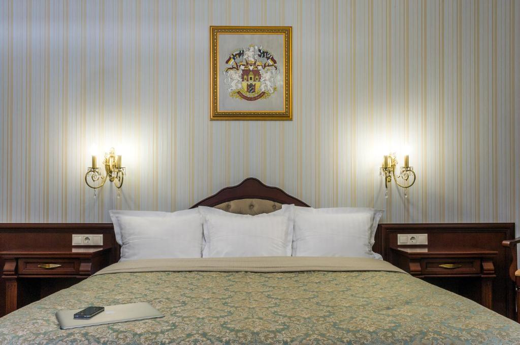 リヴィウにあるVilla Stanislavskyi Hotelのベッドルーム1室(ランプ2つ、壁に絵付)