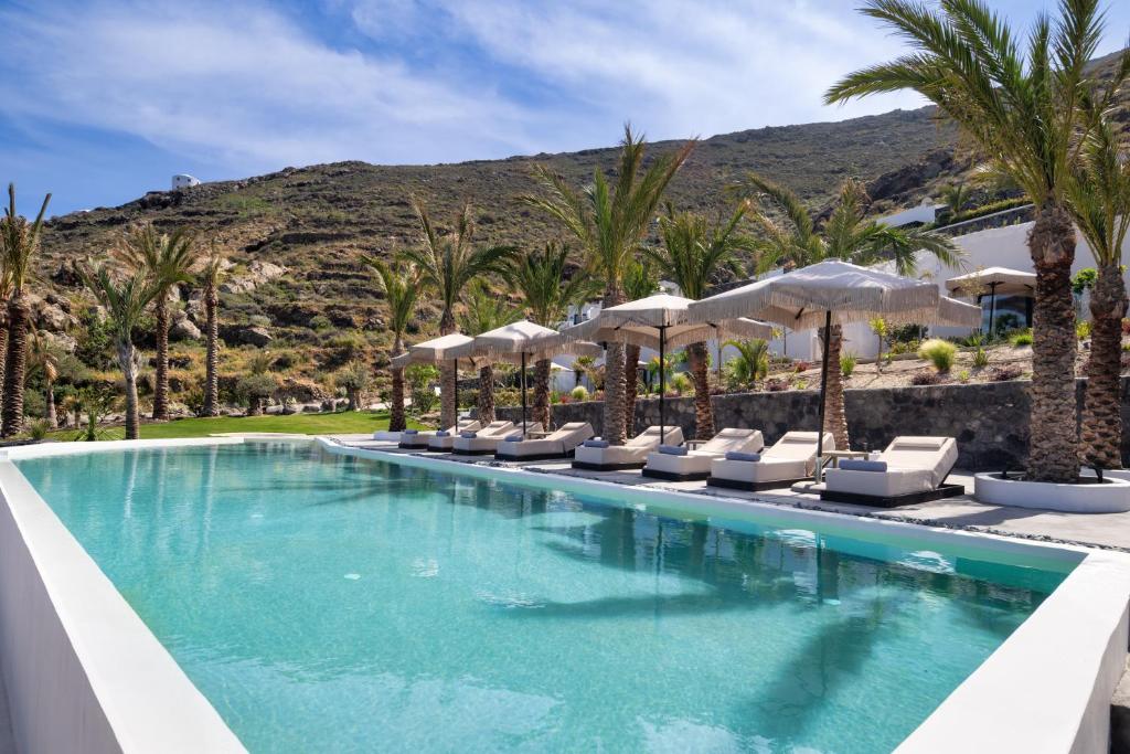 a swimming pool with chairs and umbrellas at a resort at Palm Island Suites in Imerovigli