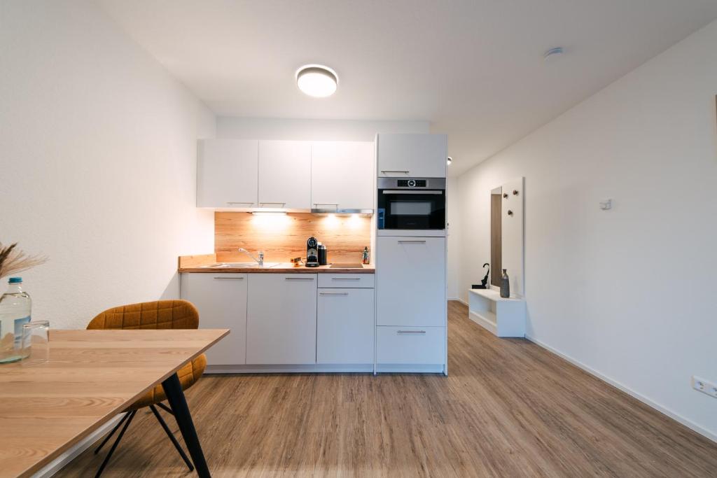 a kitchen with white cabinets and a wooden floor at ZENtrahome - Balkon Outlet Zentral SmartTV Business in Metzingen