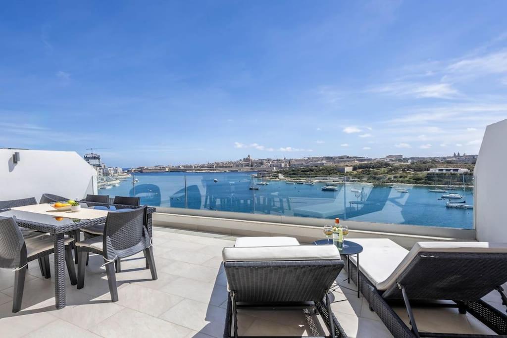 balcón con mesa, sillas y vistas al agua en Modern 3 Bedrooms Penthouse With A Breathtaking Valletta View, en Sliema