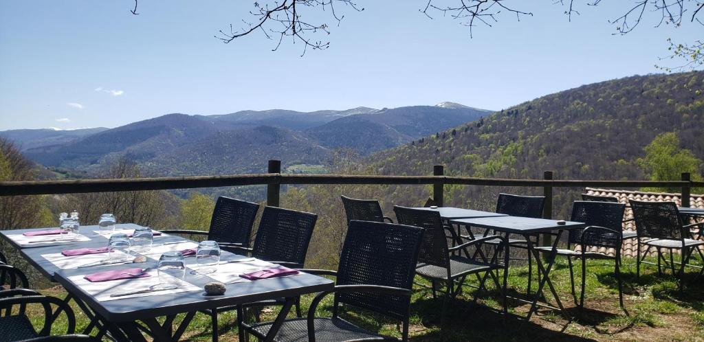 two tables and chairs on a balcony with mountains at Auberge Les Myrtilles in Le Bosc