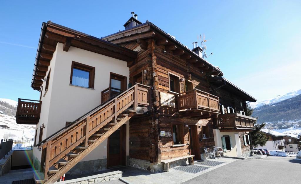 uma casa de madeira com uma escada ao lado em Casa Fiocco Di Neve em Livigno