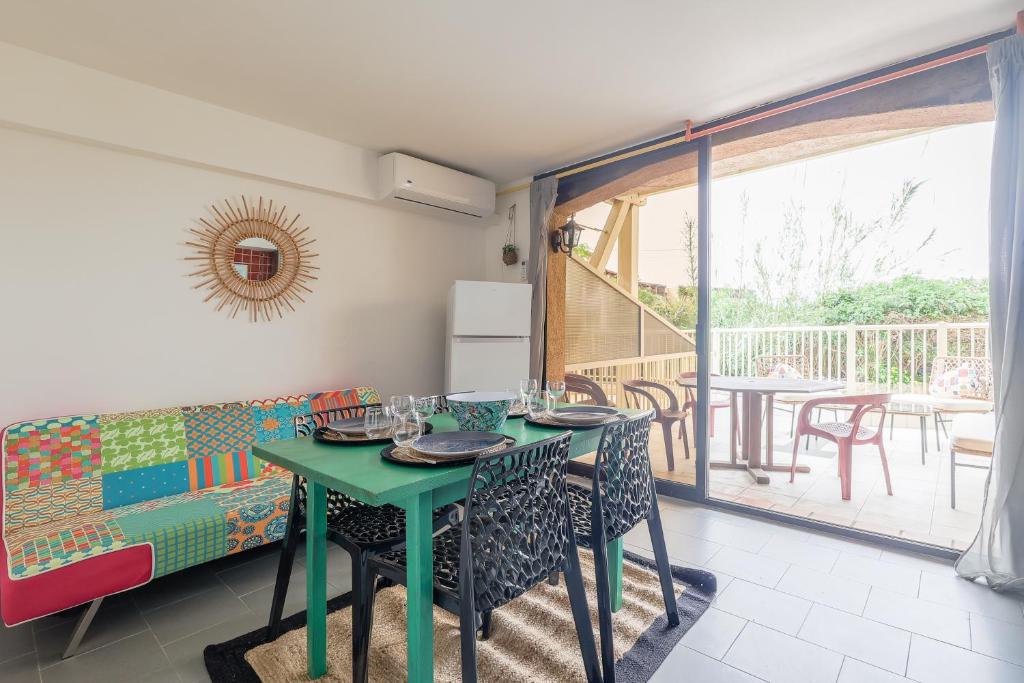 a dining room with a green table and a couch at L'Isula - Appt pour 5 climatisé avec piscine in LʼÎle-Rousse