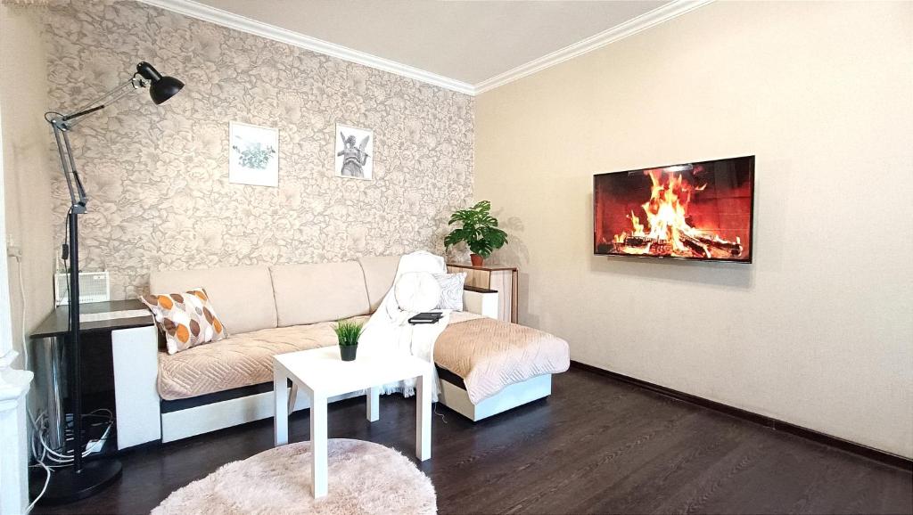 een woonkamer met een bank en een open haard aan de muur bij 2 комнатная квартира в центре города in Karagandy