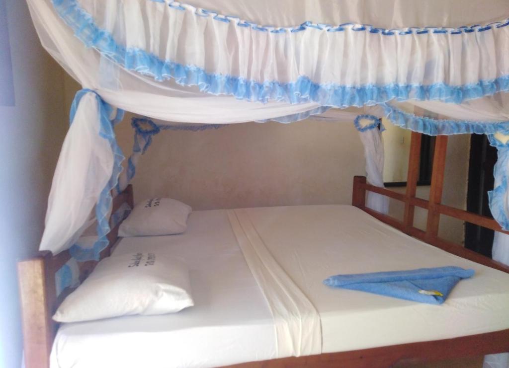 a bed in a room with a curtain and a bunk bed at Subira Guest House and Restaurant in Lamu