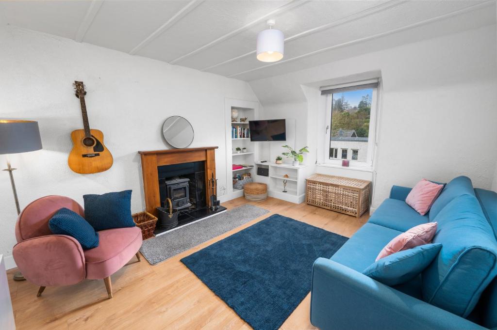 a living room with a blue couch and a fireplace at Beautiful 1 bedroom apartment with free on street parking in Oban