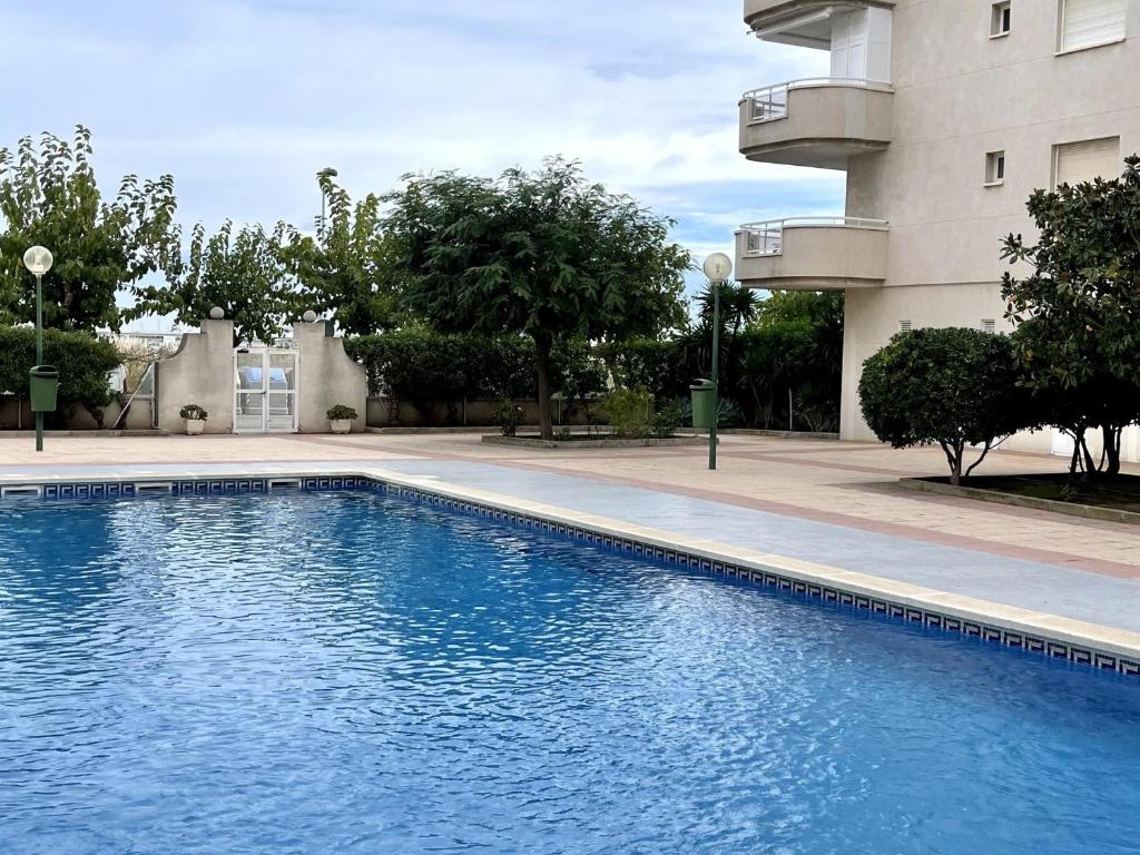 una gran piscina azul junto a un edificio en APARTBEACH MAR INTERNUM 4 JUNTO PLAYA y PISCINA en La Pineda