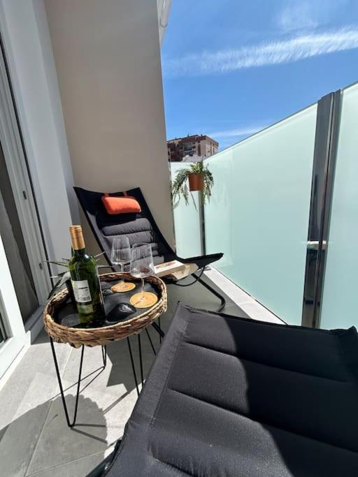 Un balcón con una botella de vino y una silla en Sol, playa y relax en Fuengirola en Fuengirola