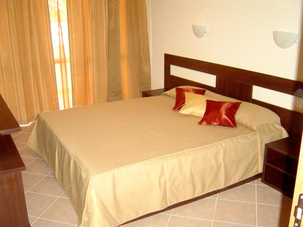 a bedroom with a bed with two red pillows on it at Sun Palace Home Apartments in Sunny Beach