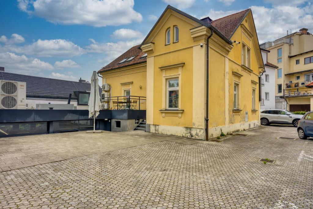 una casa amarilla en una calle con coches aparcados en Apartments Jantar - Happy Rentals en Novo Mesto