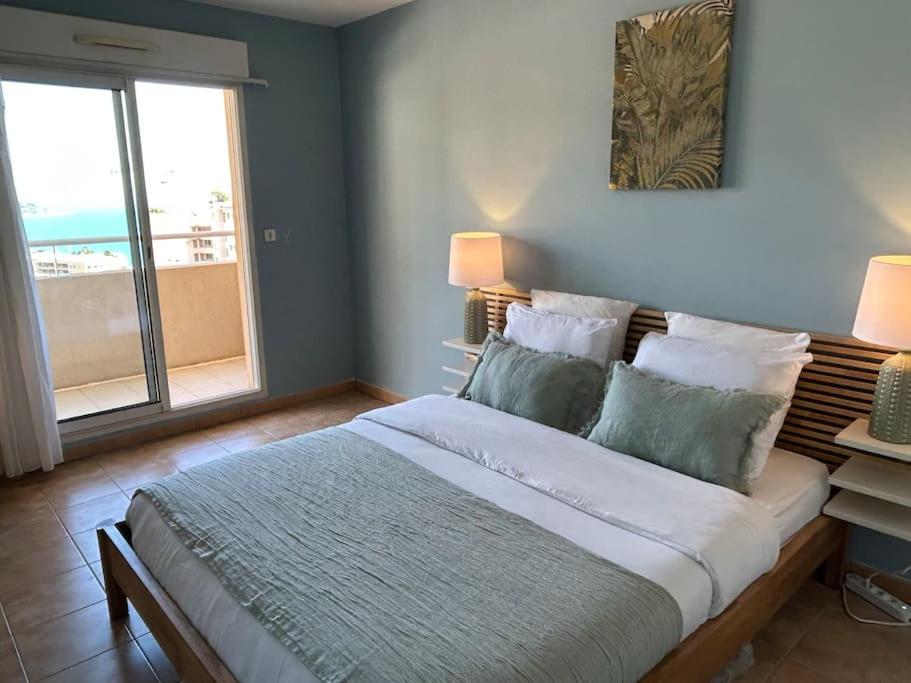 une chambre avec un grand lit et une grande fenêtre dans l'établissement Sunnydaze Monaco beach apartment, à Beausoleil