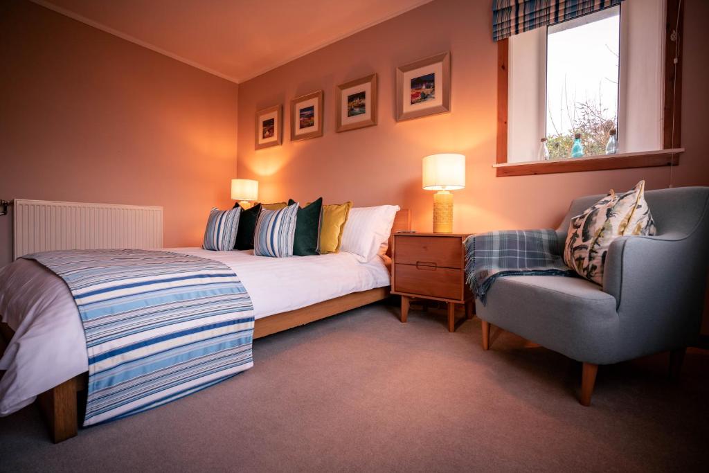 a bedroom with a bed and a chair and a window at Pabbay House Self Catering in Back