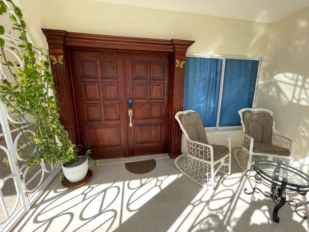 a porch with two chairs and a wooden door at Maria's Entire House HIGUEY 2BD in Higuey