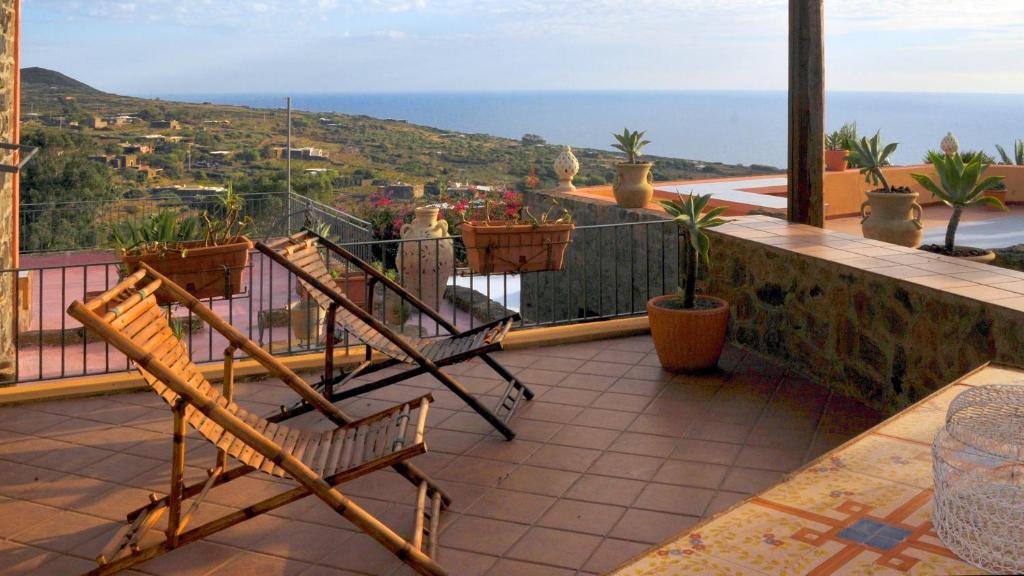 a balcony with two chairs and a view of the ocean at Sea View, Nature & BBQ - Historic "Dammusi" in Pantelleria