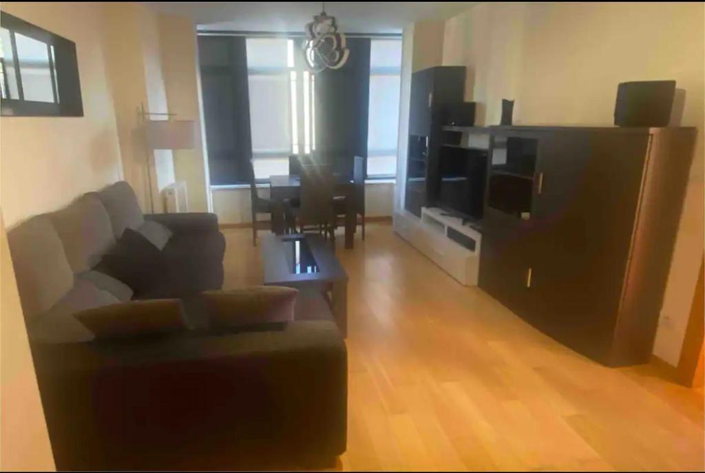 ein Wohnzimmer mit einem Sofa, einem TV und einem Tisch in der Unterkunft Apartamento Villa Termal Mondariz Balneario in Mondariz-Balneario