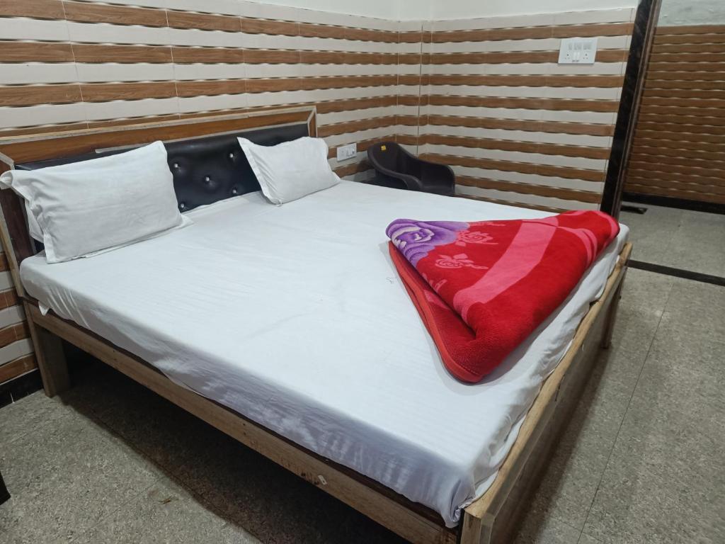 uma cama com um cobertor vermelho em cima em Babu seva em Govardhan