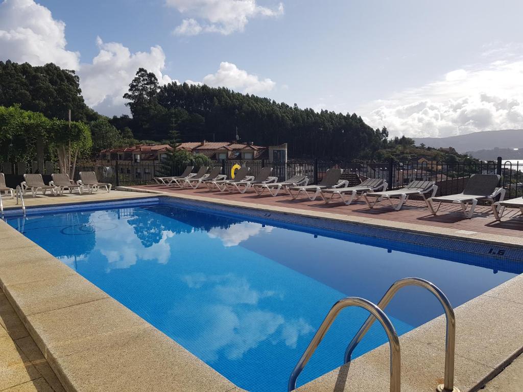a swimming pool with chairs and blue water at APARTAMENTOS CANADA 2 in Raxó