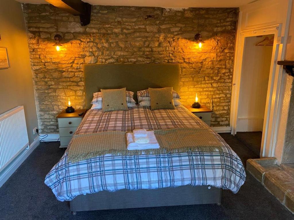 sypialnia z łóżkiem z kamienną ścianą w obiekcie BEAR INN - BISLEY w mieście Bisley