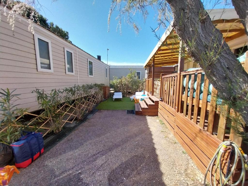une maison avec une clôture en bois à côté d'une maison dans l'établissement Mar lestang mobilhome 3chambres, à Canet