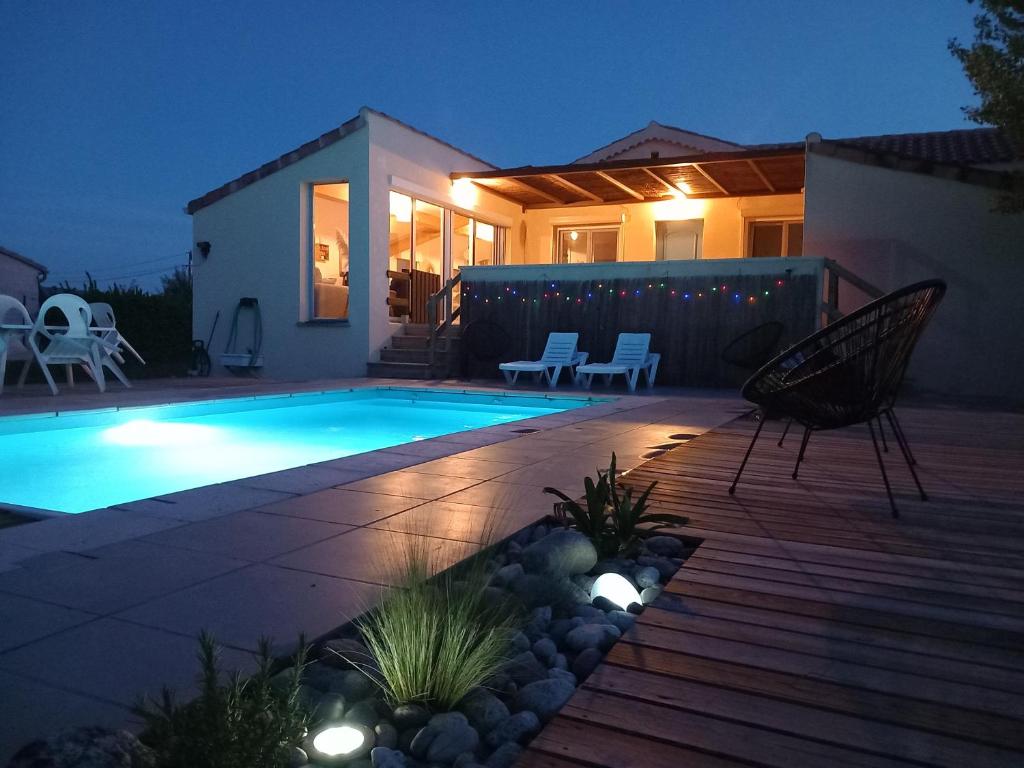 Un patio trasero con piscina por la noche. en Gîte Le vallon des vignes, en Vallon-Pont-dʼArc