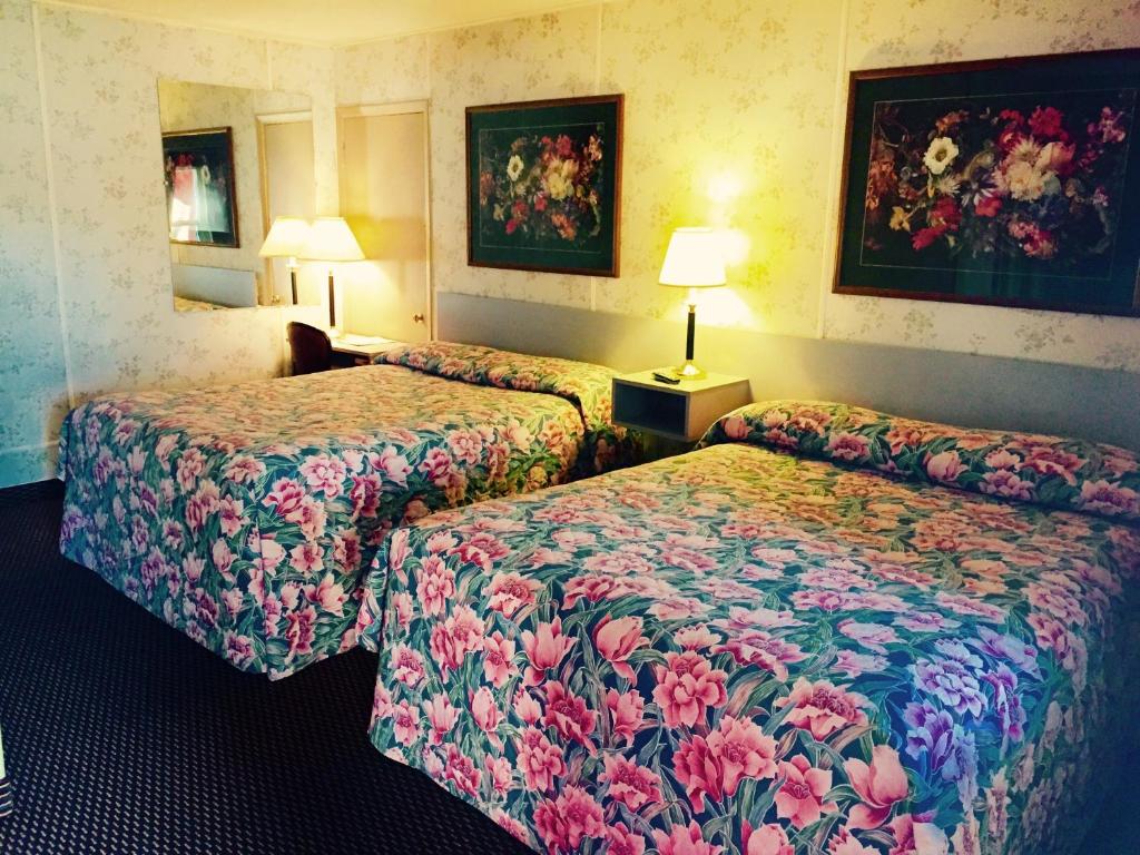 een hotelkamer met 2 bedden met bloemen bij Travelers Inn Motel in Salem