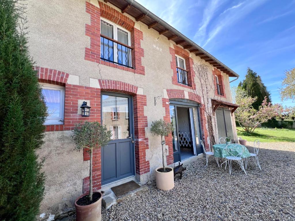 une maison en briques avec une porte bleue et une table dans l'établissement Gite Marie Ange, à Marsac