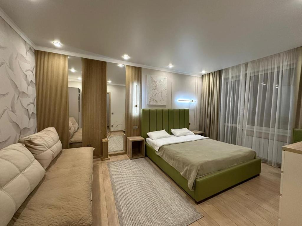 um quarto com uma cama e um sofá em Уютная, новая квартира в центре города em Qostanay