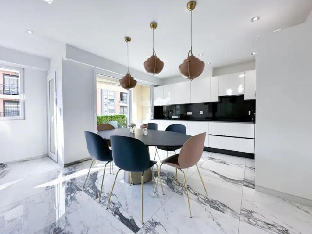 une salle à manger avec une table noire et des chaises bleues dans l'établissement Modern 3 bedroom flat with balcony, à Cannes
