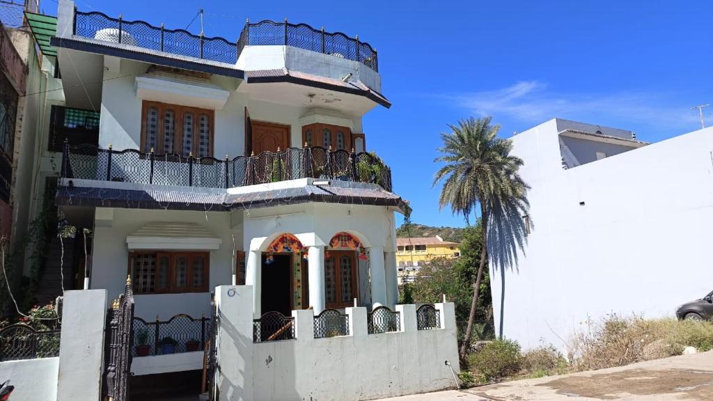 Casa blanca con balcón y palmera en Abu Banglow, en Mount Abu