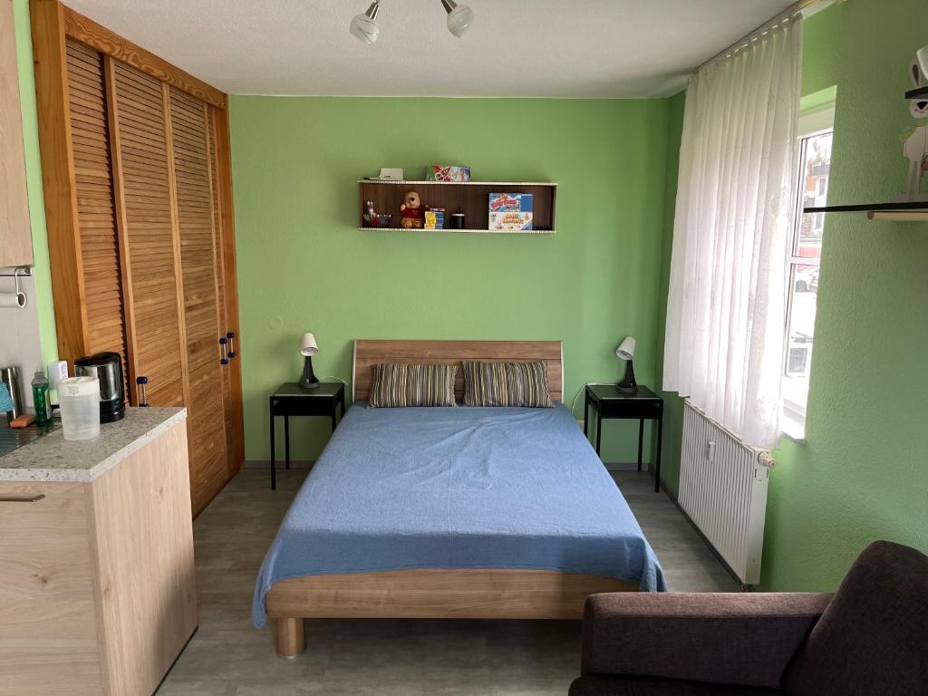 ein Schlafzimmer mit einem blauen Bett und grünen Wänden in der Unterkunft Marienkäfer in Braunlage