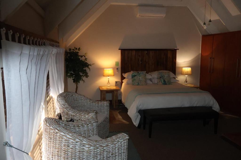 - une chambre avec un lit et deux chaises en osier dans l'établissement The Leopard Tree, à Polokwane