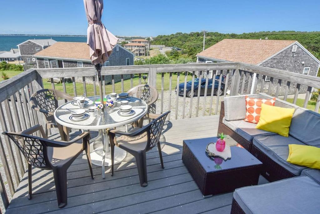 un patio con mesa, sillas y sombrilla en 12216 - Beautiful Views of Cape Cod Bay Access to Private Beach Easy Access to P-Town, en Truro