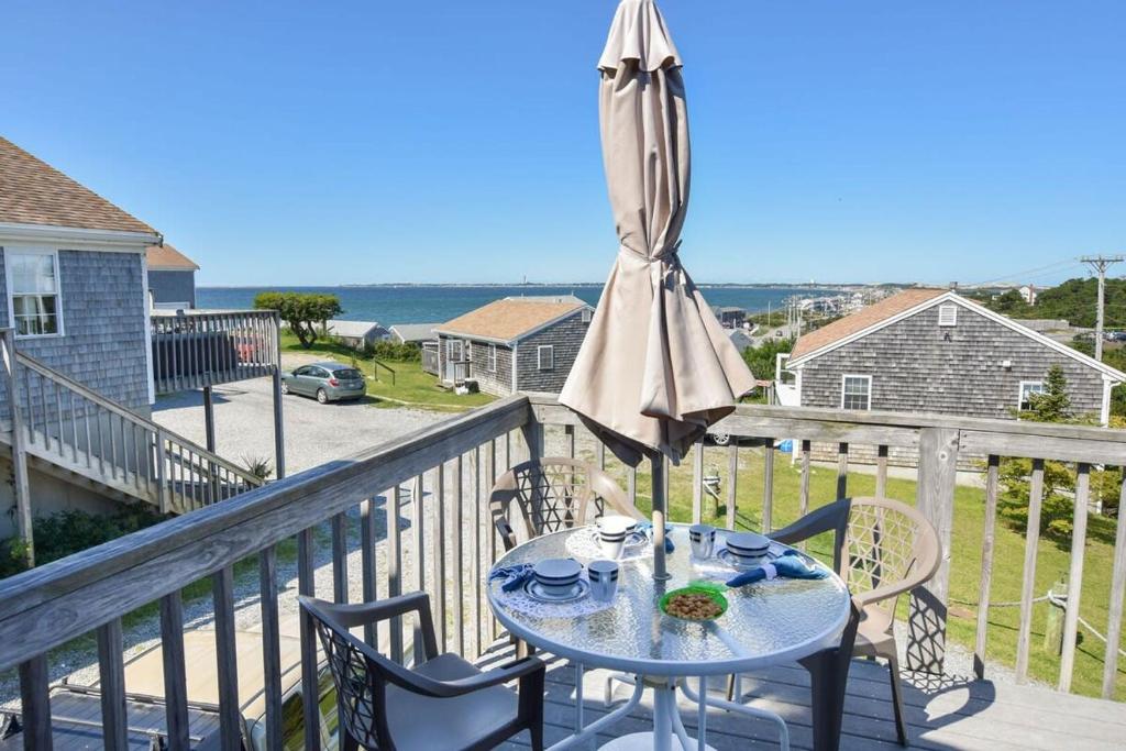 a table with an umbrella and chairs on a balcony at 12217 - Beautiful Views of Cape Cod Bay Access to Private Beach Easy Access to P-Town in Truro