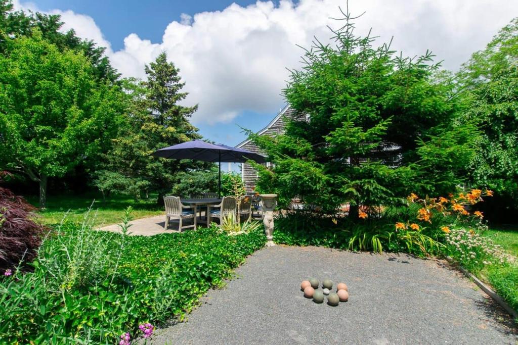 un patio con una mesa y una sombrilla en un jardín en Stunning Home by Beach Bocce Court, en Truro